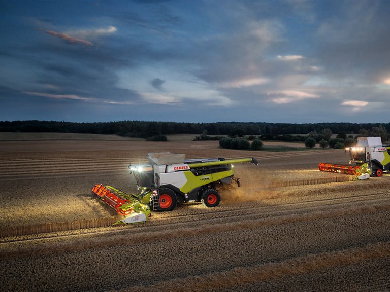 460034_27 LEXION 6900 and CONVIO 1080 harvesting wheat in the dark with work lights on.